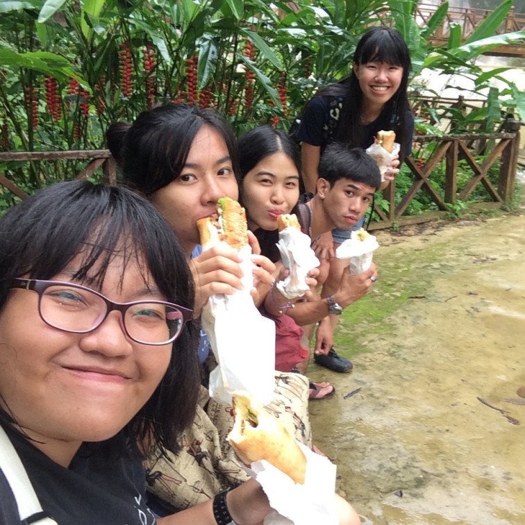 Student guides and traveller enjoying French baguettes at Kuang Si Waterfall, Luang Prabang